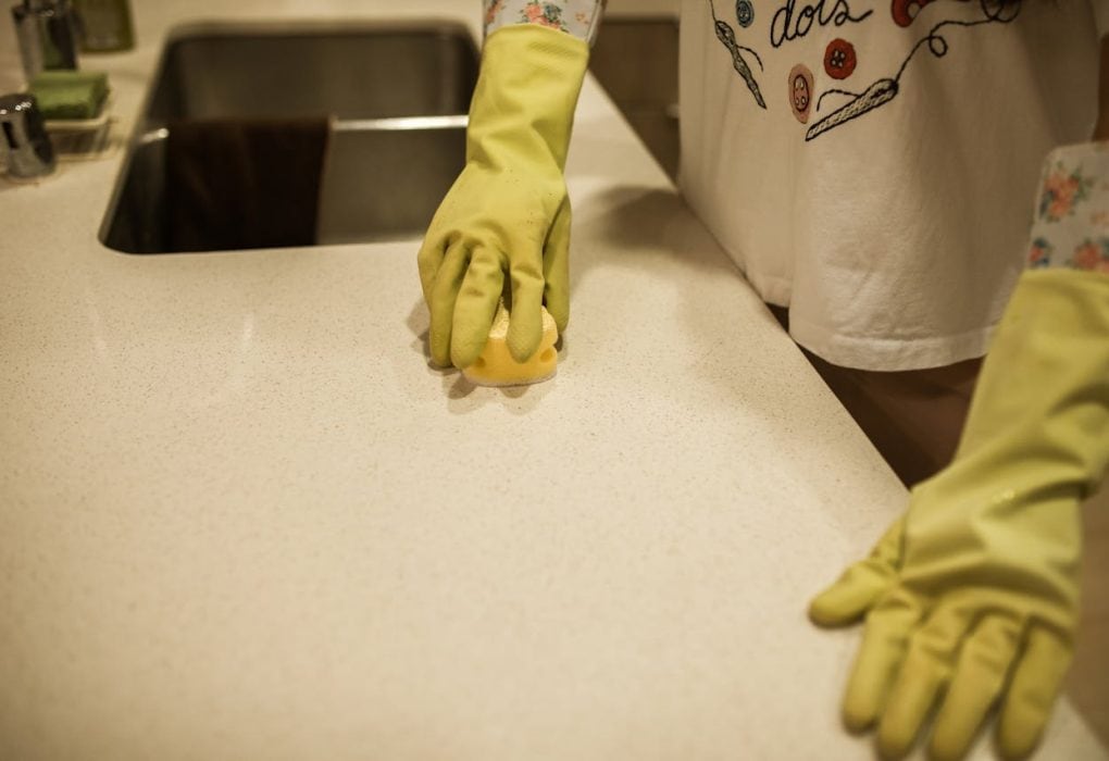 Person reinigt Küchenarbeitsplatte mit Gelb-Handschuhen, professionelle Großküchenreinigung Hamburg.